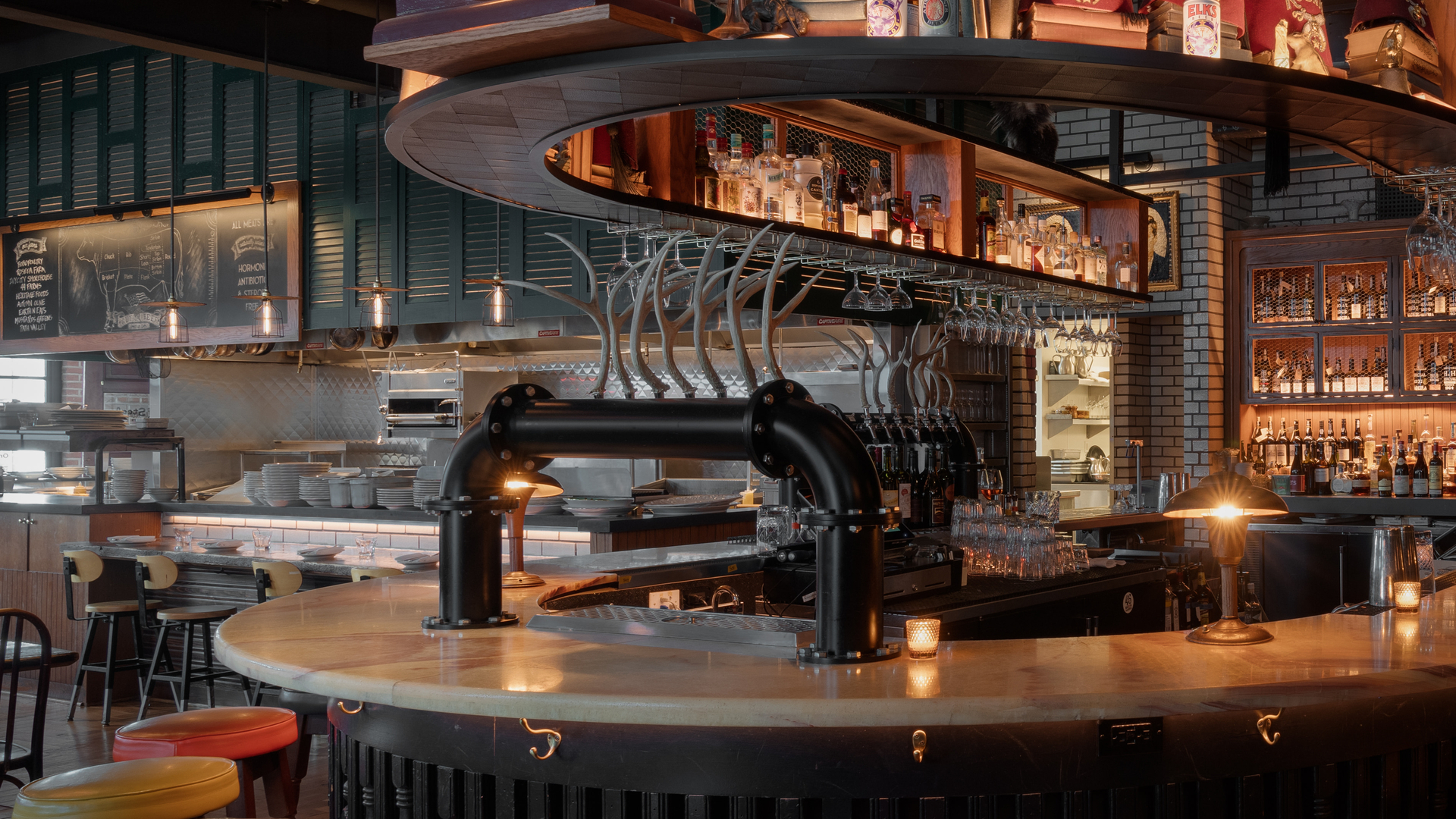 Circular bar with stools, clock, shelves, and industrial-style décor in a dimly lit restaurant setting.